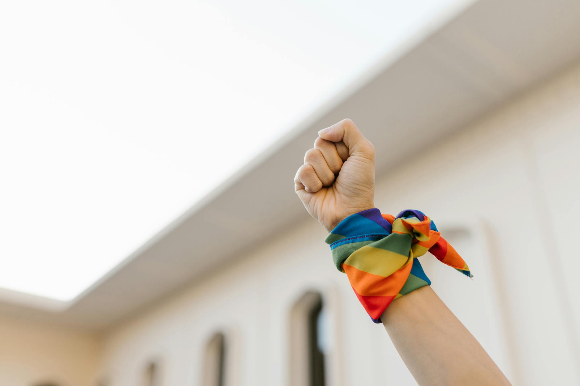 unrecognizable raised fist and wrist wrapped in rainbow cloth