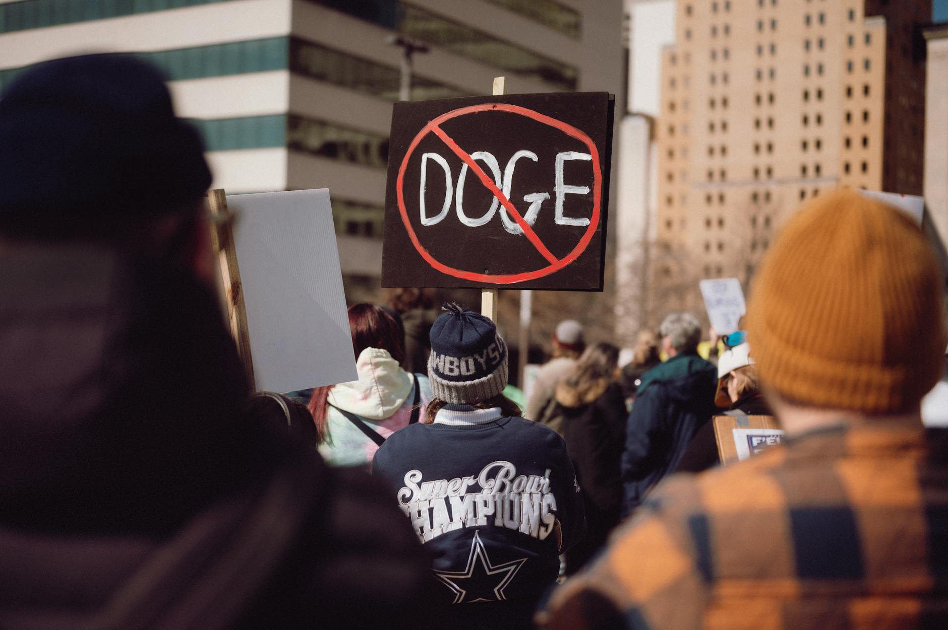 crowd at protest with doge meme sign